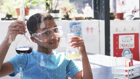 Boy holding two flasks in science lab, tilting right flask, causing animated Stock Footage 334373041