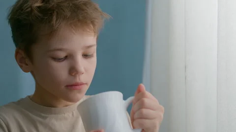 Boy is holding a white mug, drinking warm tea Stock Footage 326168145