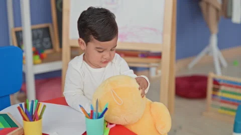 Boy holding a yellow plush teddy at a preschool art studio table with color.. Stock Footage 339186495