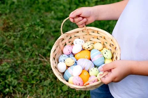 A boy holds a basket of Easter eggs in his hands against a background Stock Photos