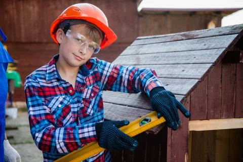 The boy holds the building level, checking the accuracy of the dog house roof Stock Photos