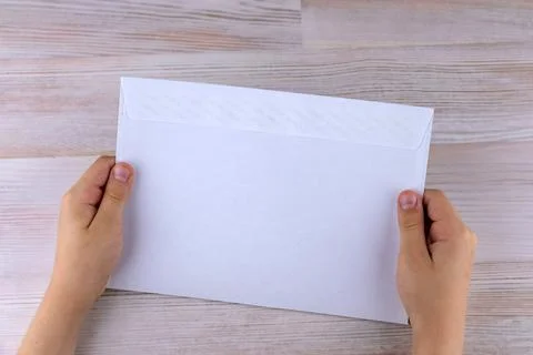 The boy holds an empty envelope with free space for inscriptions Stock Photos