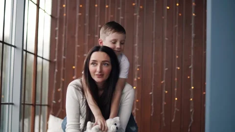 Boy hugs his mom from behind while holding a toy puppy Stock Footage 141897447