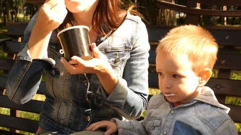 Boy indulges sitting on a bench in the Park. The child is dirty in the ice cream Stock Footage 94052105