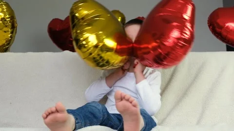 Boy is indulging with a red and gold heart-shaped balloon Stock Footage 146163843