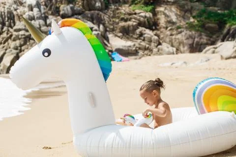 Boy with inflatable unicorn on the beach Фото