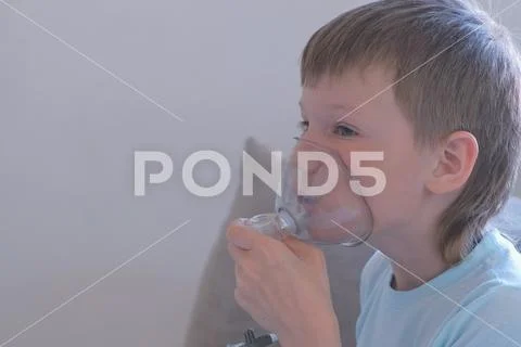 Boy inhaling through inhaler mask. Use nebulizer and inhaler for the treatment. Stock Photos