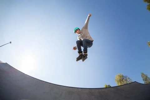 Boy with inline skates, rollerblade, doing a jump in a skate park Stock Photos