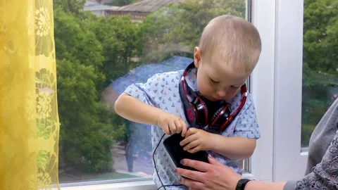 The boy inserts headphones into a mobile phone Stock Footage 137966918