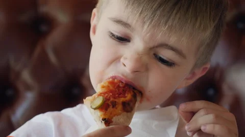 A boy is intently eating a slice of pizza, holding it firmly with both hands Stock Footage 277797201