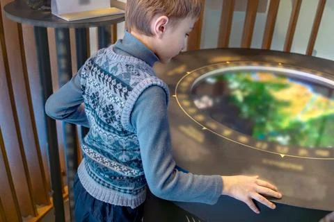 Boy interacts with a circular interactive screen at an exhibit. Like fairy ta Stock Photos