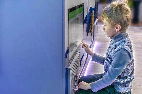 A boy interacts with an interactive screen at an exhibit. Copy space Stock Photos