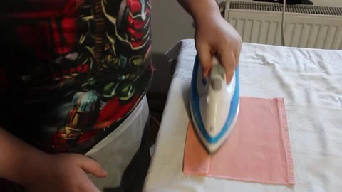 The boy is ironing a napkin with an iron on the table Stock Footage 245554660