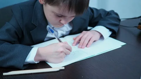 A boy in a jacket draws a graph in a notebook. young financier Stock Footage 144179878