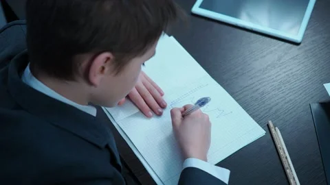 A boy in a jacket draws graphs in a notebook Stock Footage 144179961