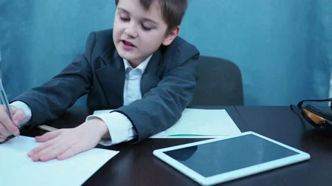 A boy in a jacket makes notes on a piece of paper. distance learning Stock Footage 144179995