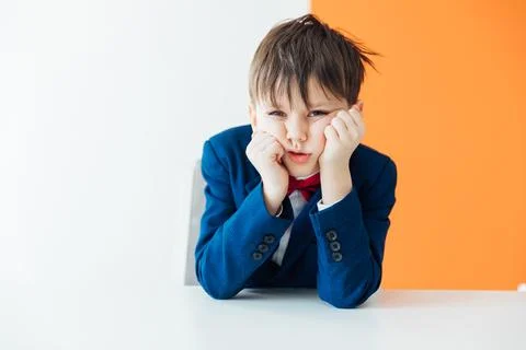 Boy in jacket tired sitting at table Stock Photos