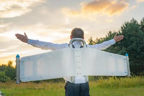 Boy in jetpack wings playing on a meadow. Open arms Stock Photos
