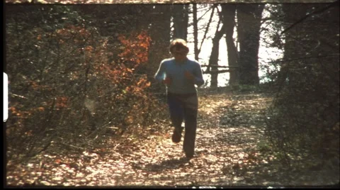 Boy jogging through forest (vintage 8 mm amateur film) Stock Footage 998547