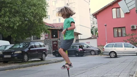 A boy joyfully performs tricks on a pogo stick, experiencing excitement and Stock Footage 251648393