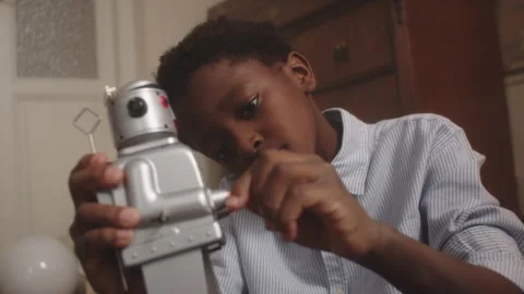 Boy joyfully plays with retro toy robot in cozy indoor setting Stock Footage 319912051