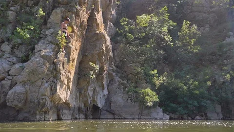 A boy jumped into the river from the high rocks Stock Footage 114624085