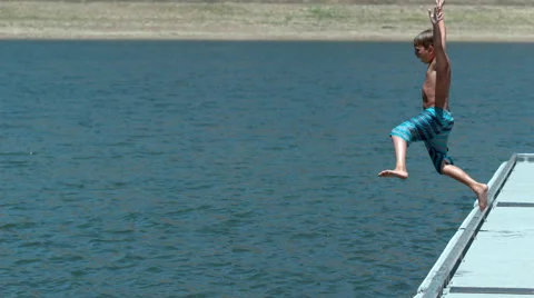Boy jumping off dock into lake in super slow motion Stock Footage