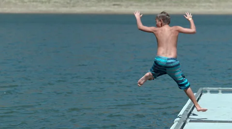Boy jumping off dock into lake in super slow motion Stock Footage