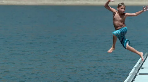Boy jumping off dock into lake in super slow motion Stock Footage