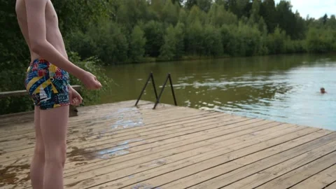 Boy jumping into the lake from the pier Stock Footage 208679841