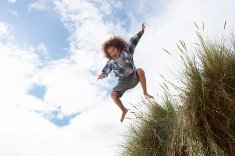 Boy jumping over dune Stock-Fotos