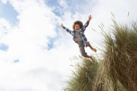 Boy jumping over dune Stock Photos