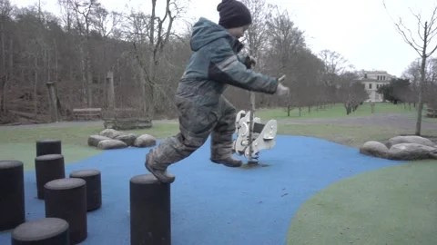 Boy jumping off playground stump in slow motion Stock Footage 231752250