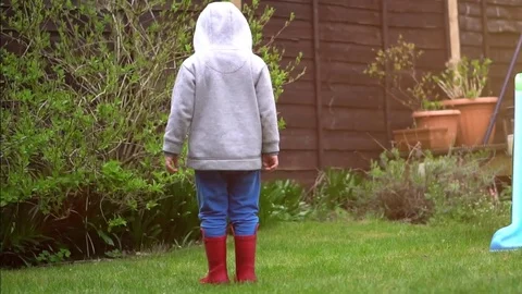Boy jumping on the puddle on the lawn Stock Footage 80238066