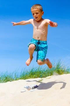 Boy jumping from a sand dune Stock Photos