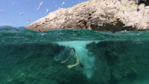 Boy jumping into sea water split shot over under half underwater view 스톡 동영상 338180788