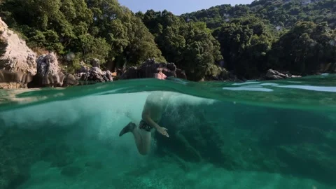 Boy jumping into sea water split shot over under half underwater view 스톡 동영상 338180877