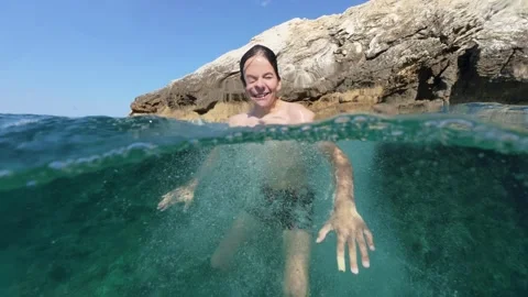 Boy jumping into sea water split shot over under half underwater view 스톡 동영상 338180920