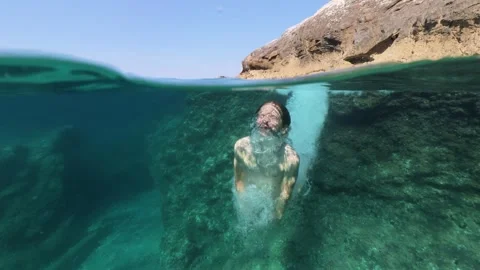Boy jumping into sea water split shot over under half underwater view 스톡 동영상 338180927