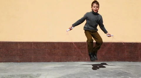 Boy jumping on skipping rope in yard Stock Footage 956633