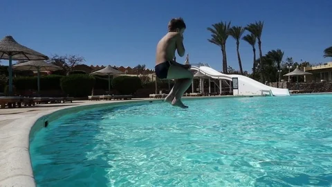 Boy jumping in swimming pool, slow motion Stock Footage 73395945