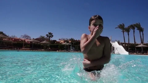 Boy jumping in swimming pool with splash, slow motion Stock Footage 73396211