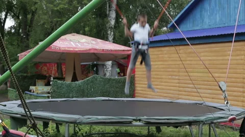 A boy jumping on the trampoline in the summer park Stock Footage 65521697