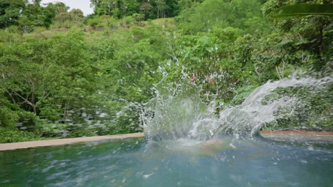 Boy Jumping Into Tropical Infinity Pool in Slow Motion with Jungle Background. Stock Footage 338363515