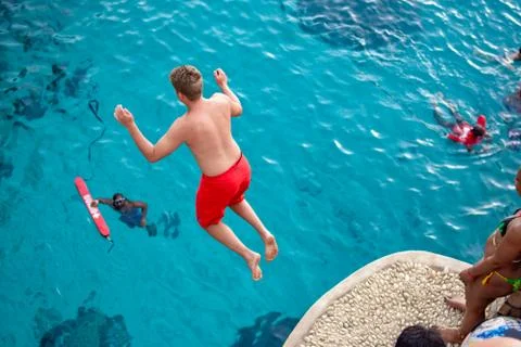 Boy jumping into the water from cliff Stock Photos