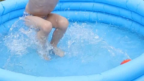 Boy jumps and splashes in inflatable pool Vídeo Stock 111513266