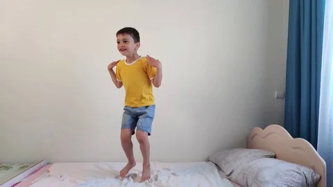 Boy jumps on the bed Stock Footage 129974738
