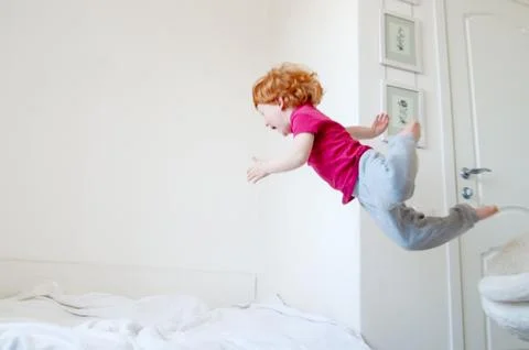 The boy jumps on the bed Stock Photos