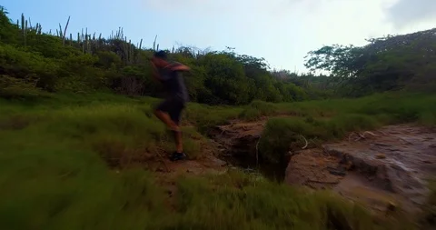 Boy jumps over small pond off water in nature Stock-Footage 97768648