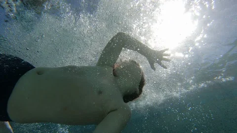 Boy Jumps Into Pool with Sun Stockbeeldmateriaal 129729200